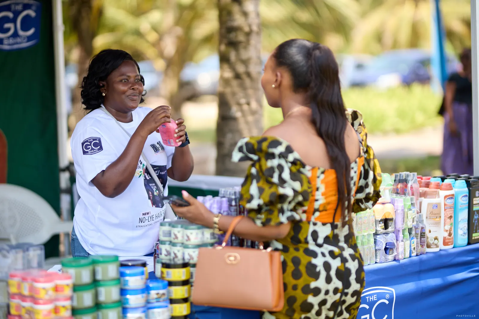Vendor showing hair-care products to a guest at a branded stall